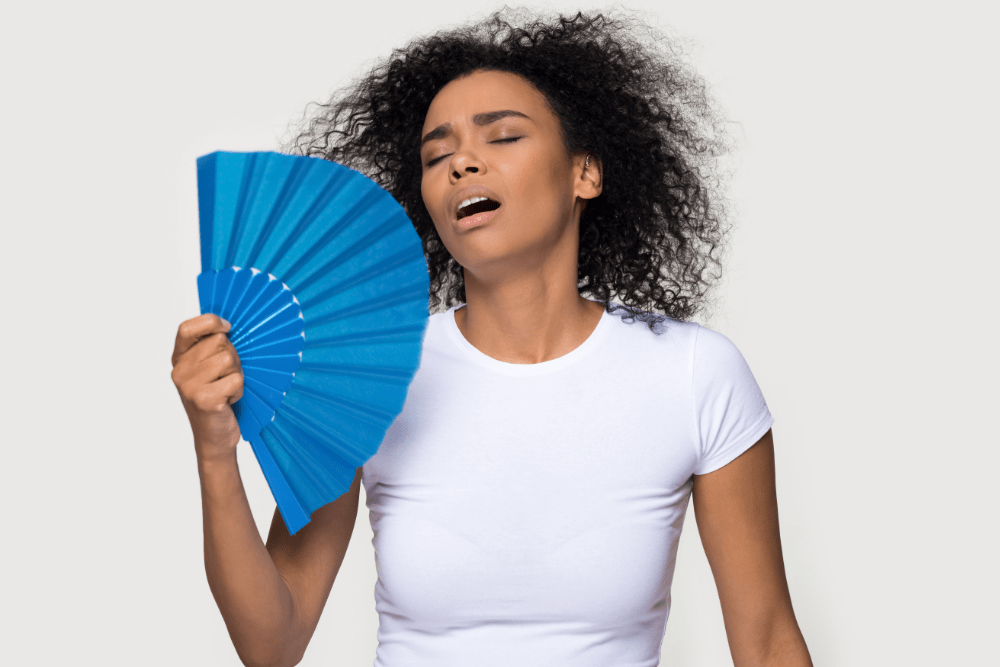 A lady with a hand fan feeling hot and dehydrated.